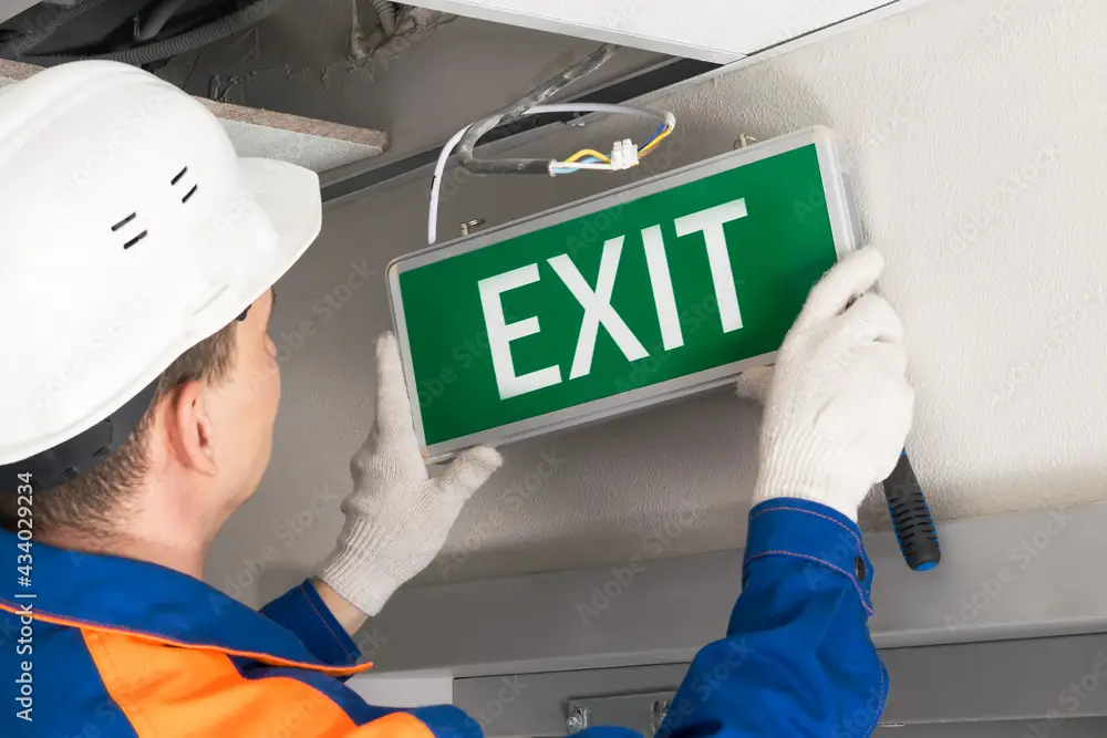 foreman completes installation of lighting signs emergency exit